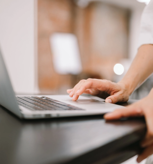 WordPress Schulung: geordneter Arbeitsplatz mit Laptop, orange Bleistift und Spiralnotizbuch auf weißem Tisch, Kaffeetasse im Hintergrund